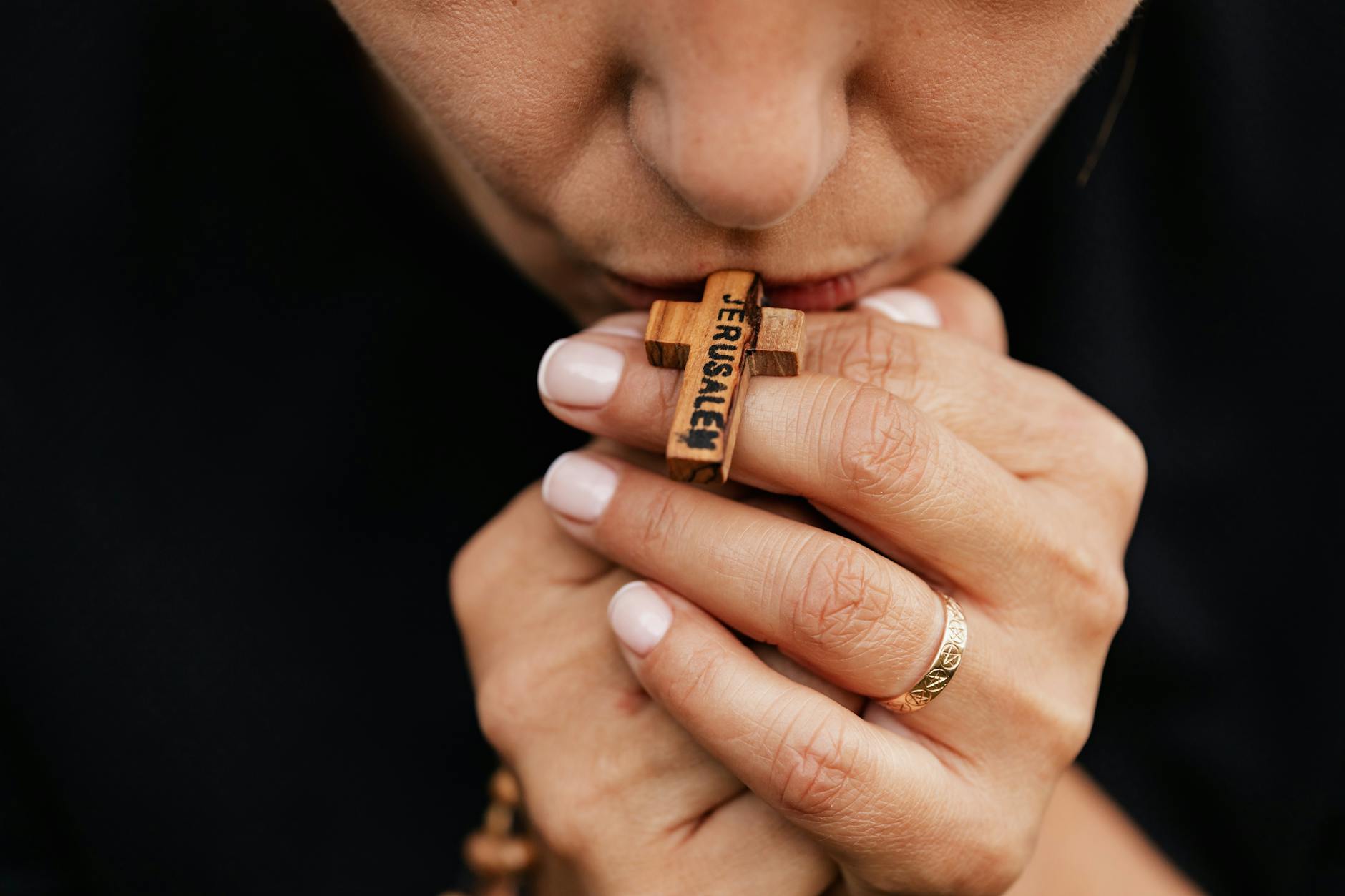 close up shot of a person holding while kissing a rosary